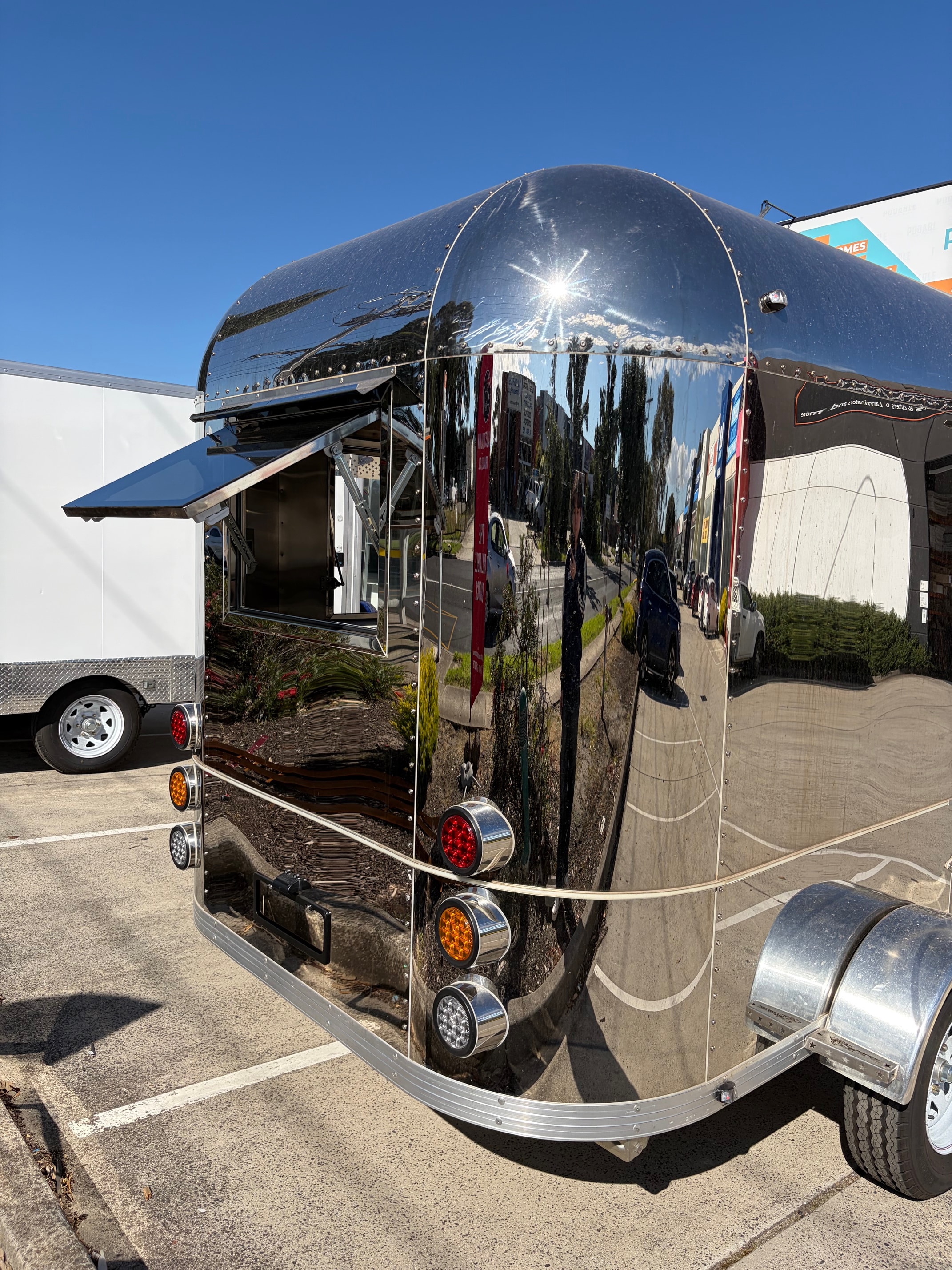 Rear exterior of polished Airstream food trailer with triple LED tail lights in car park