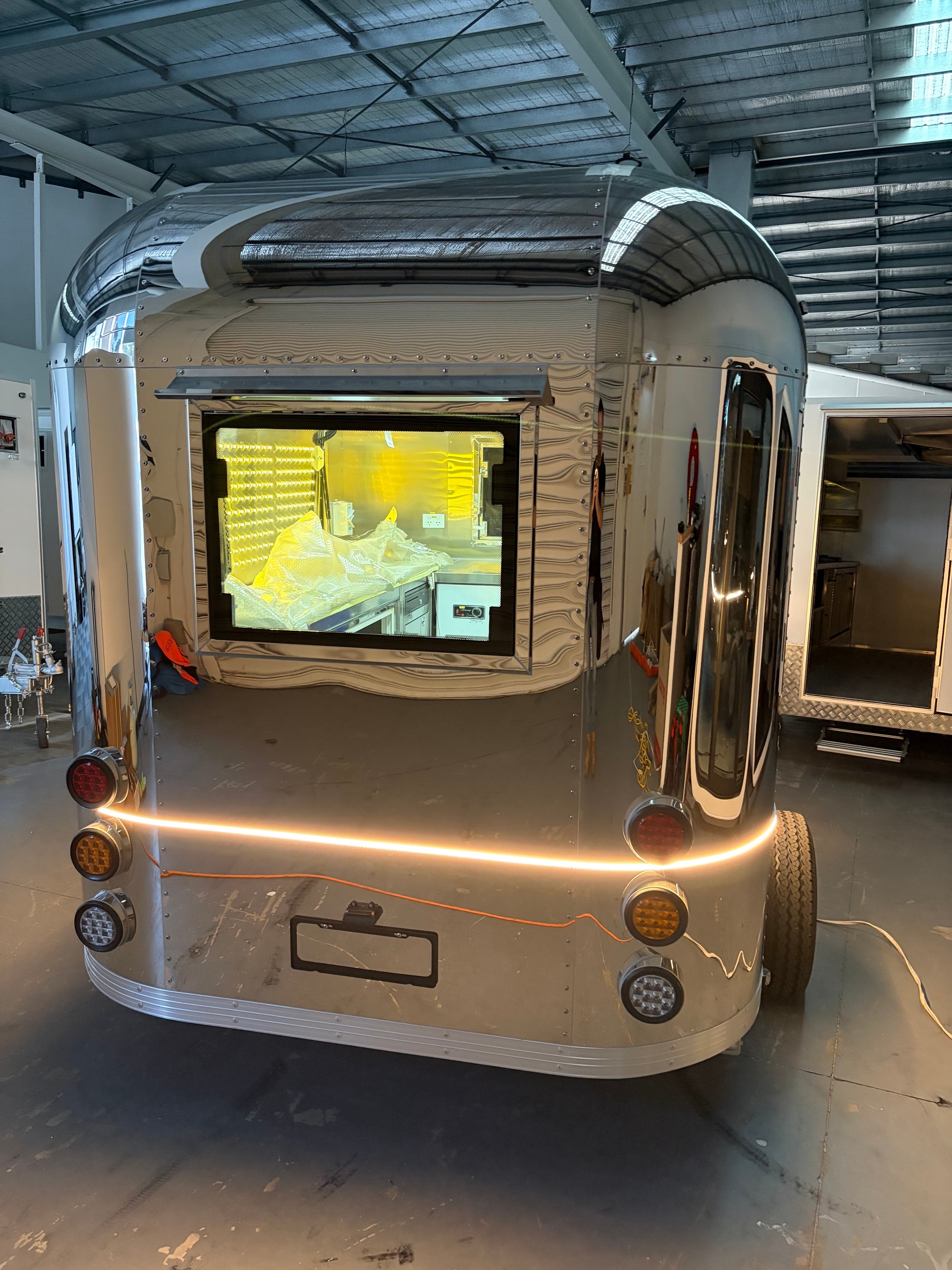 Rear view of polished Airstream trailer showing LED tail lights and serving hatch
