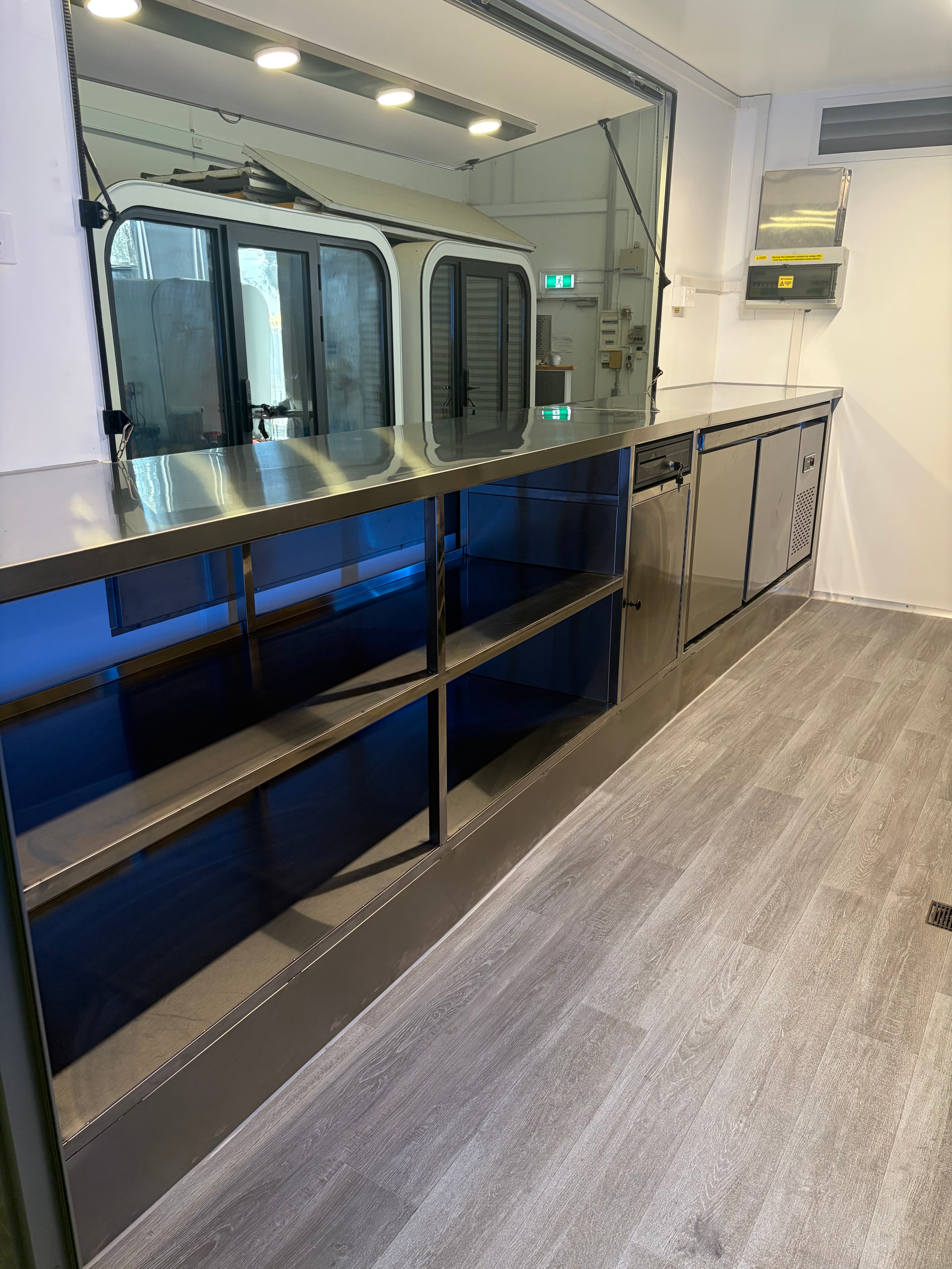 Food trailer interior showing storage compartments with blue LED lighting and service window