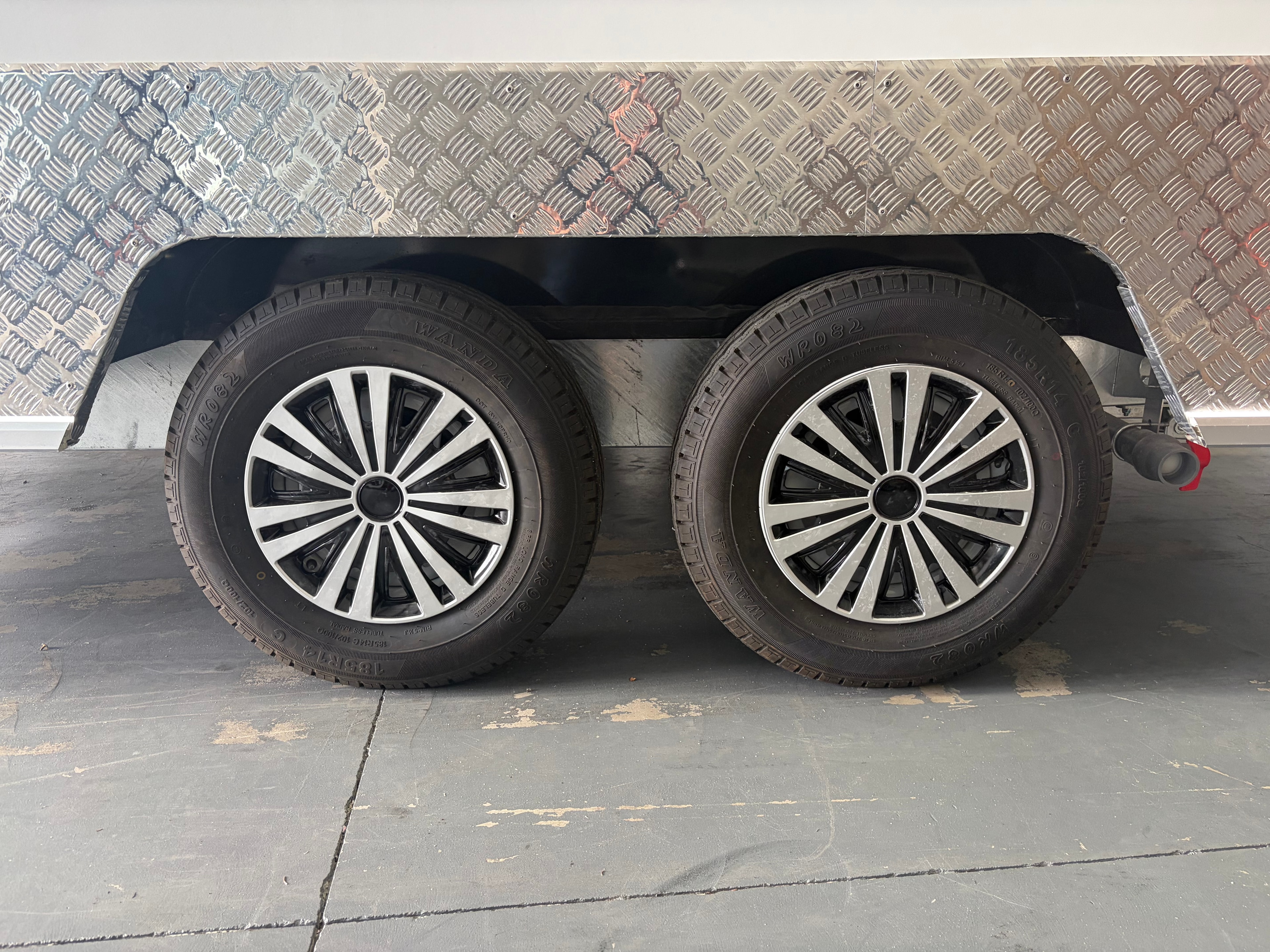 Close-up of food trailer dual axle with twin Wanda alloy wheels on checker plate