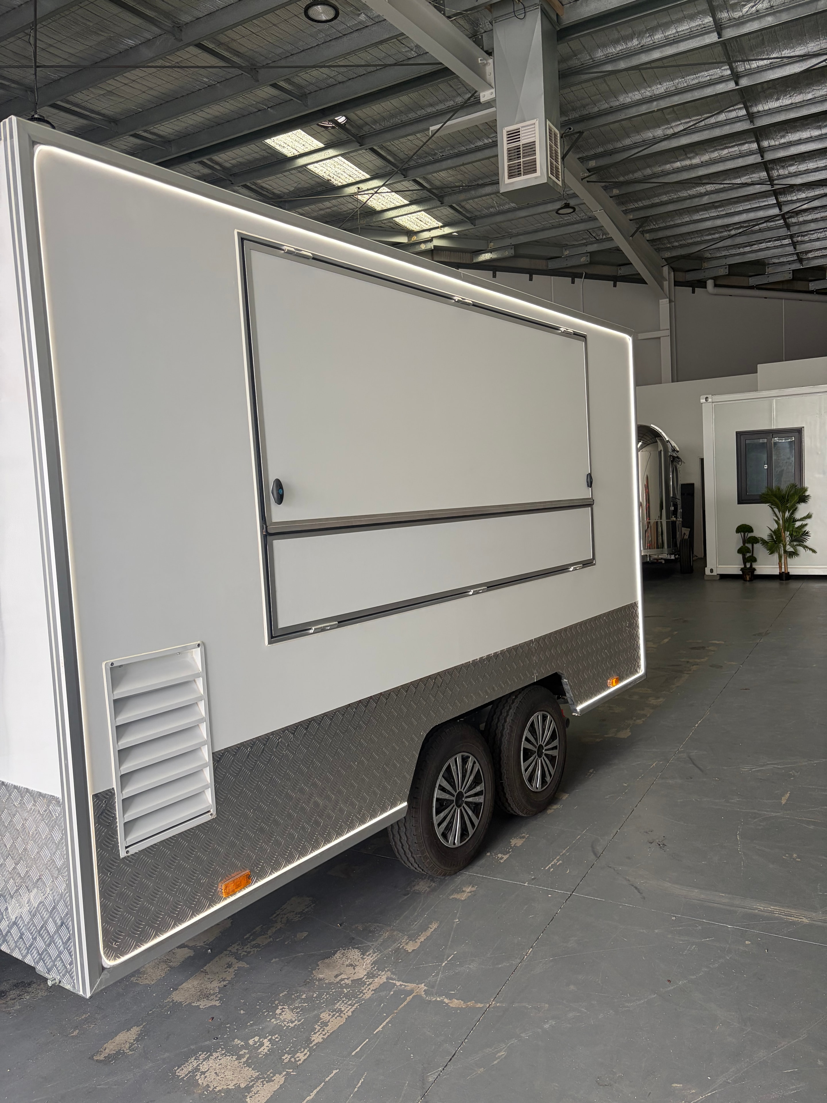 Aerial view of food trailer with hatch open revealing stainless steel commercial kitchen interior