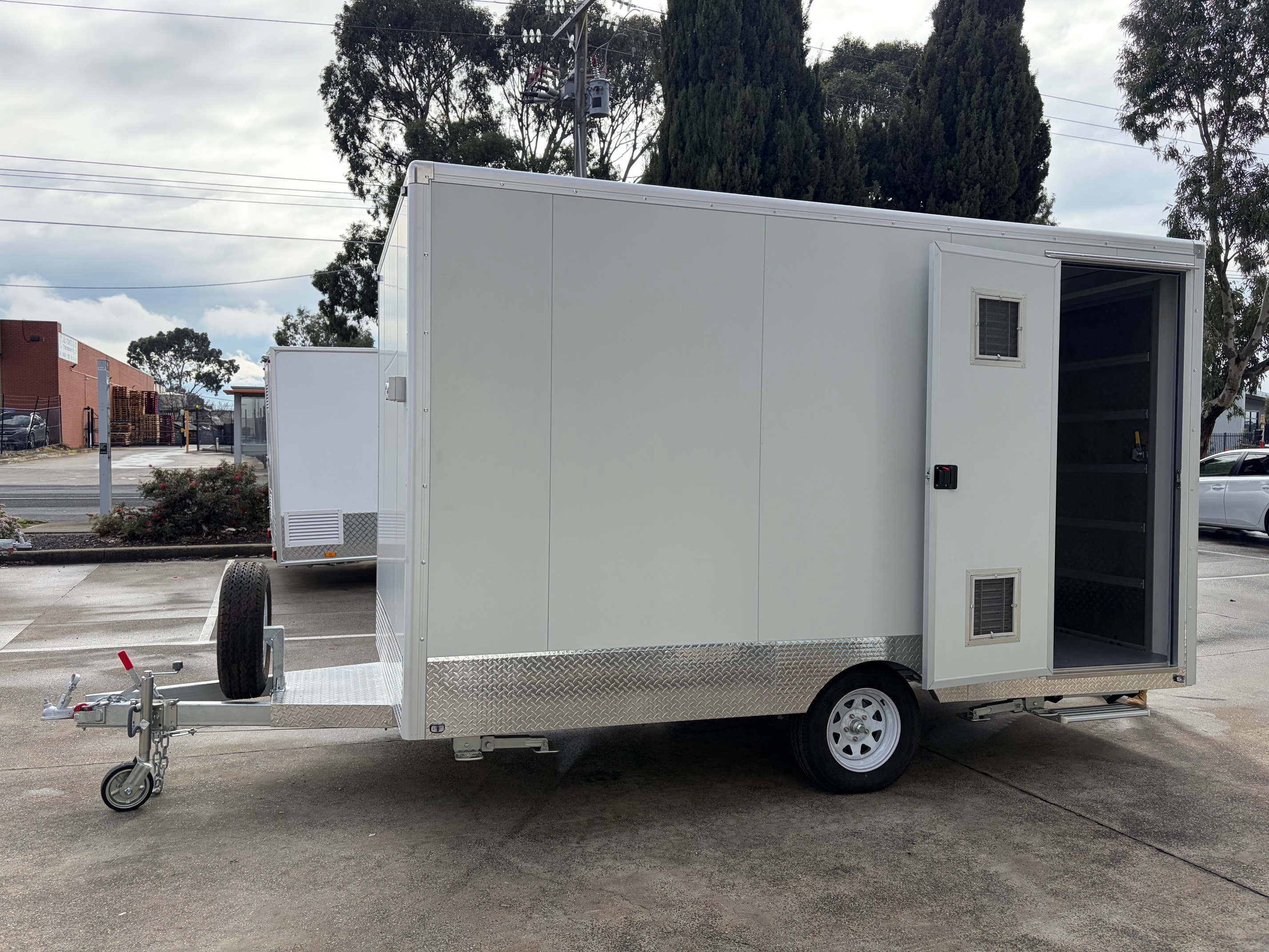 White enclosed trailer with an open side entry door, exterior trim and single axle