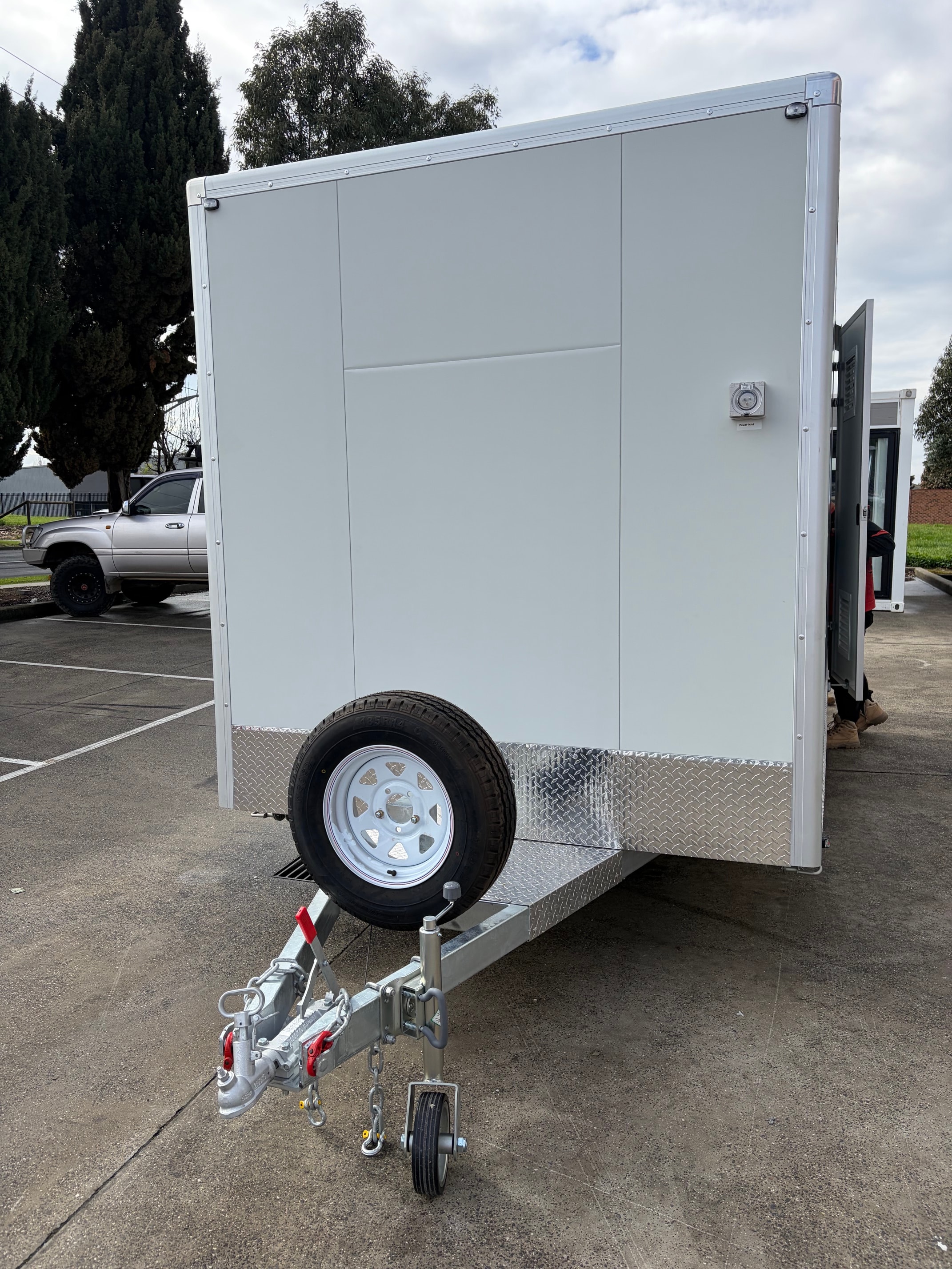 White enclosed trailer side profile with diamond-plate trim, wheel and hitch